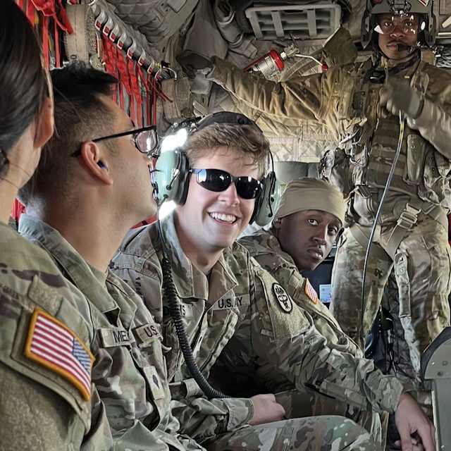 Shane in uniform smiling inside an Army helicopter with fellow soldiers